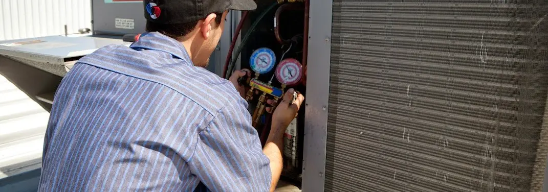 HVAC technician servicing a condenser unit in Calumet